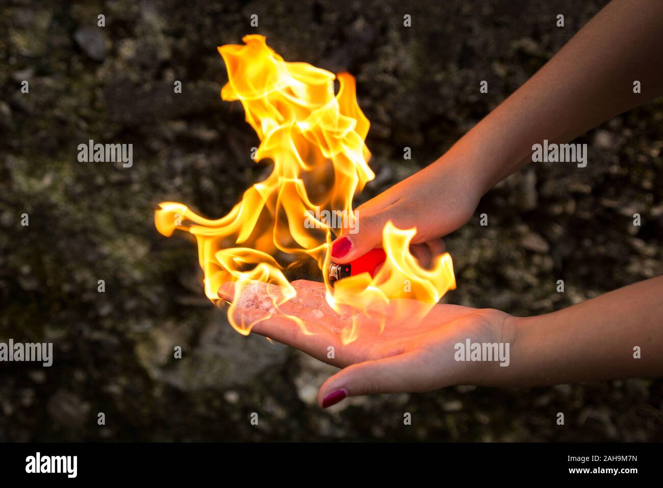 Mano sul fuoco, giovani donne mano con un accendino, giocando con il fuoco Foto Stock