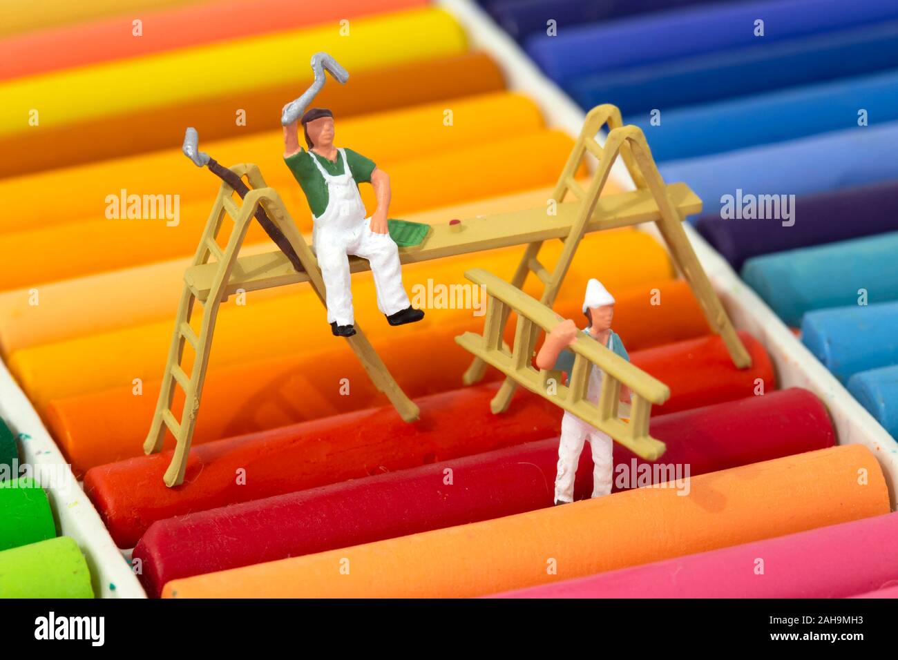 Miniatura modello in scala di pittori e decoratori con scale su un set di pastello olio pastelli. Concetto di decorazione Foto Stock
