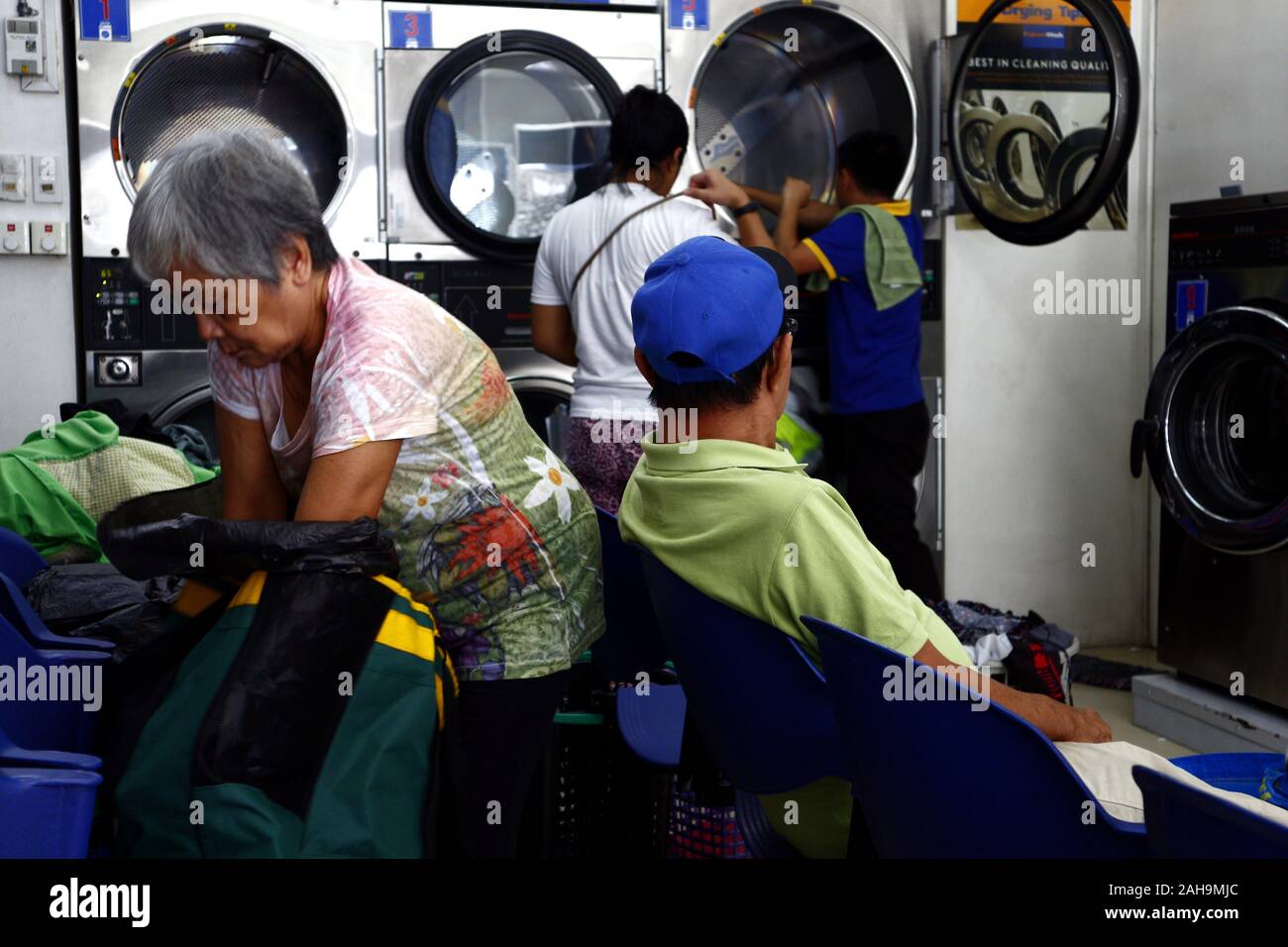 Antipolo City, Filippine - 21 dicembre 2019: i clienti a una lavanderia a sedersi e aspettare per i loro abiti per essere terminato il lavaggio. Foto Stock
