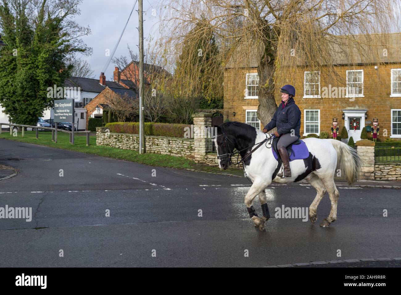 La donna a cavallo throurh grazioso villaggio di Milton Malsor, Northamptonshire, Regno Unito Foto Stock