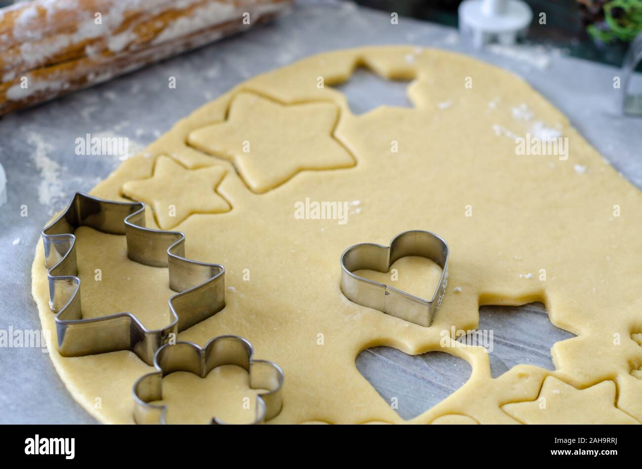 La preparazione di biscotti di Natale utilizzando cookie cutter e un matterello. Il fuoco selettivo sulla fresa e pasta biscotto Foto Stock