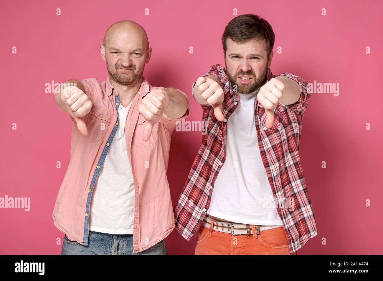 Due uomini, mostrando un brutto segno e antipatia, fare un pollice giù gesto, con una grimace di disapprovazione sui loro volti. Foto Stock