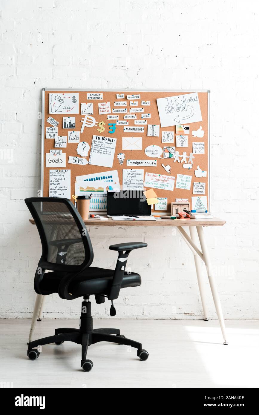 Bacheca con scritte sui foglietti adesivi e vicino al tavolo e sedia Foto Stock