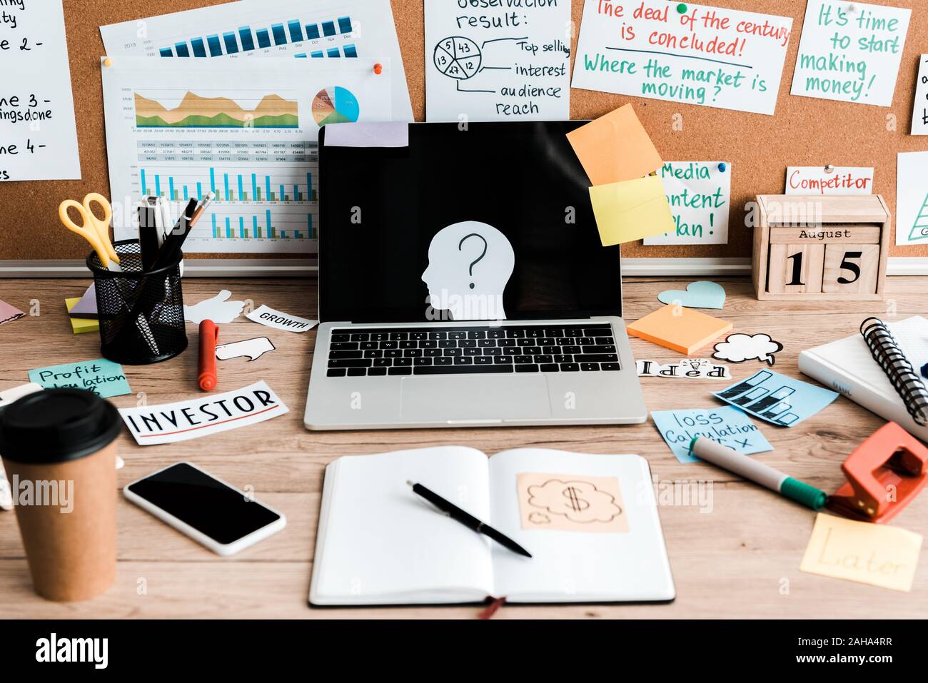 Laptop e smartphone con schermi vuoti sul tavolo vicino a bacheca con lettere e note adesive Foto Stock