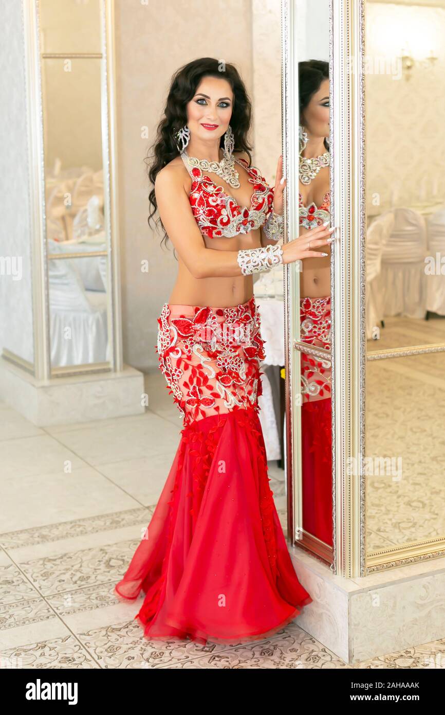 Una donna orientale di 35-40 anni sorge nei pressi di un grande specchio nella lobby dell'hotel. Foto Stock