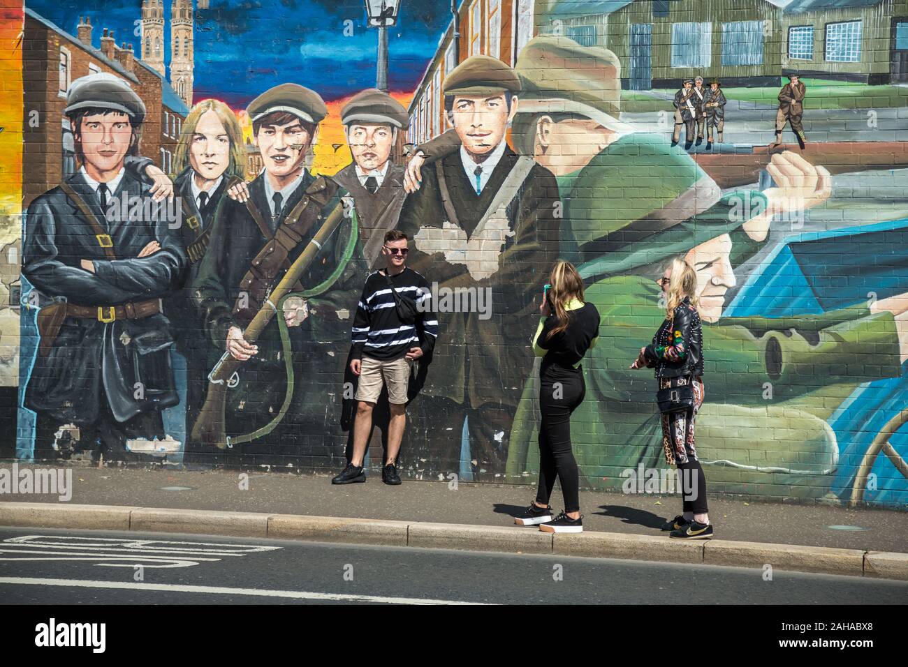 14.07.2019, Belfast, Irlanda del Nord e Gran Bretagna - giovani turisti, politico murale, Falls Road, Occidente Cattolico di Belfast. Le pitture murali sono state dipinte in Foto Stock