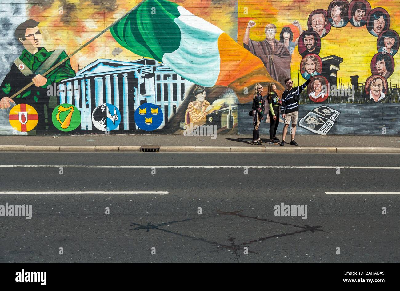 14.07.2019, Belfast, Irlanda del Nord e Gran Bretagna - giovani turisti, politico murale, Falls Road, Occidente Cattolico di Belfast. Le pitture murali sono state dipinte in Foto Stock