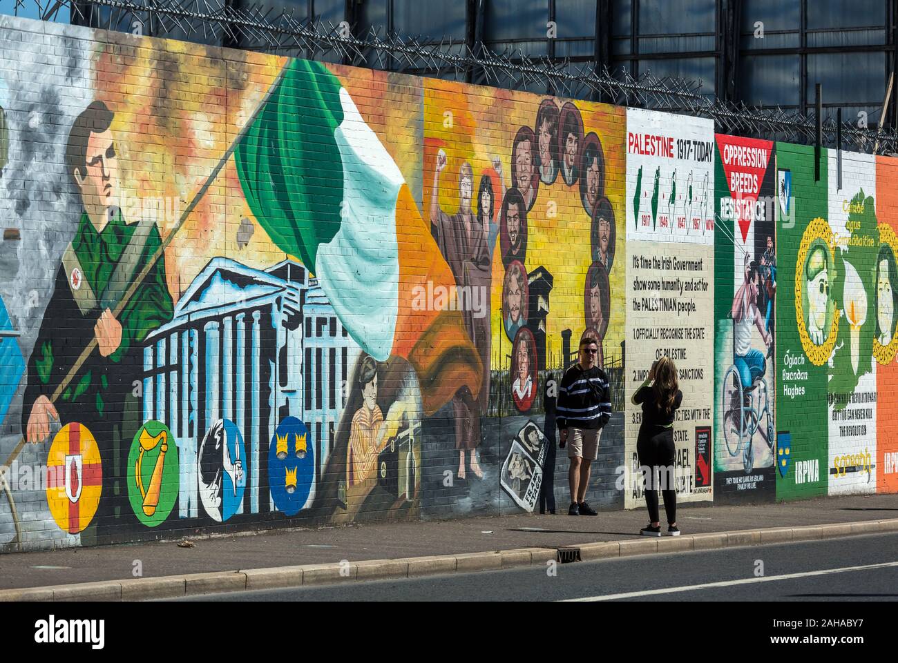 14.07.2019, Belfast, Irlanda del Nord e Gran Bretagna - giovani turisti, politico murale, Falls Road, Occidente Cattolico di Belfast. Le pitture murali sono state dipinte in Foto Stock