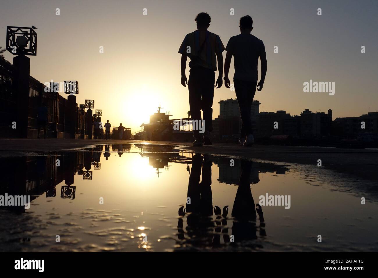 26.03.2018, Dubai, Emirati Arabi Uniti - Gli adolescenti sono riflessi in una pozza al tramonto. 00S180326D279CAROEX.JPG [modello di rilascio: NO, proprietà RELEAS Foto Stock