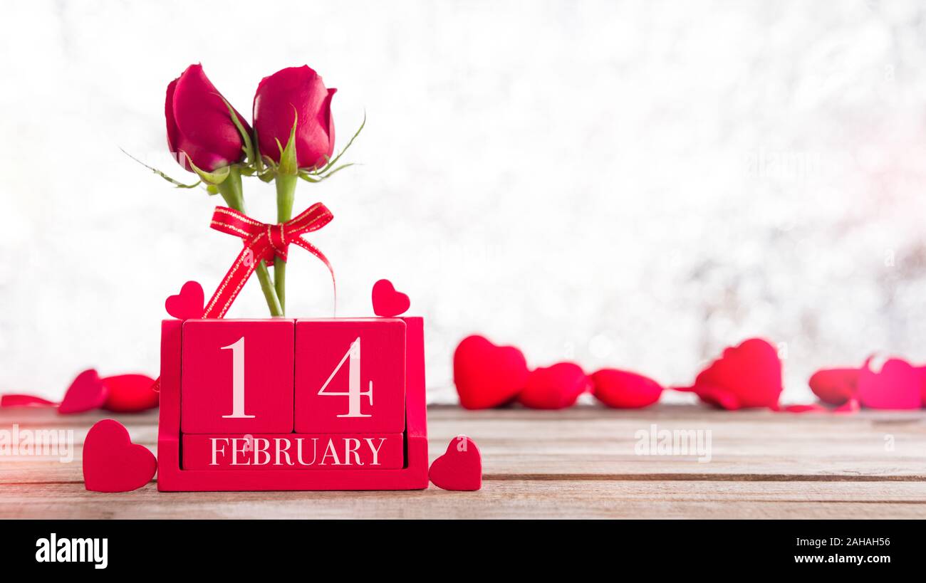 Il giorno di San Valentino sfondo. Febbraio 14 scritte sui cubi rossi e rose in background Foto Stock
