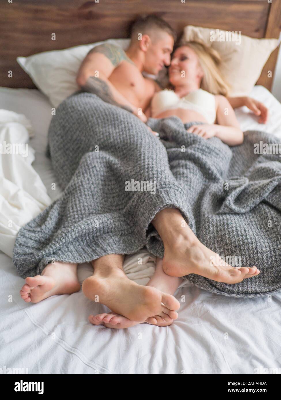 Coppia giovane rilassante a letto insieme, toccando le gambe. Focuc sui piedi. Amore e relazioni concetto Foto Stock