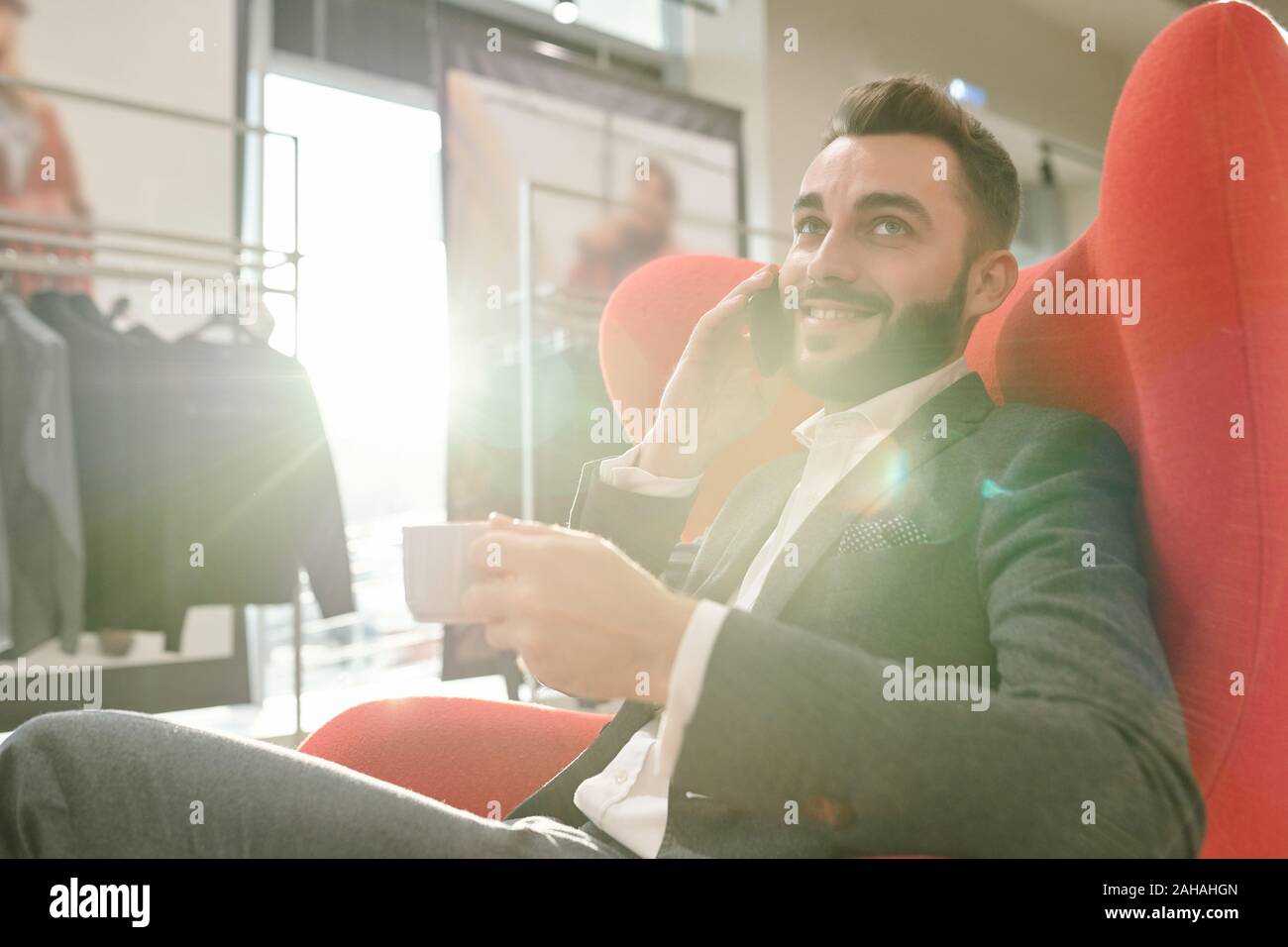 Giovane imprenditore di successo con la tazza di tè consulting client dal telefono cellulare Foto Stock