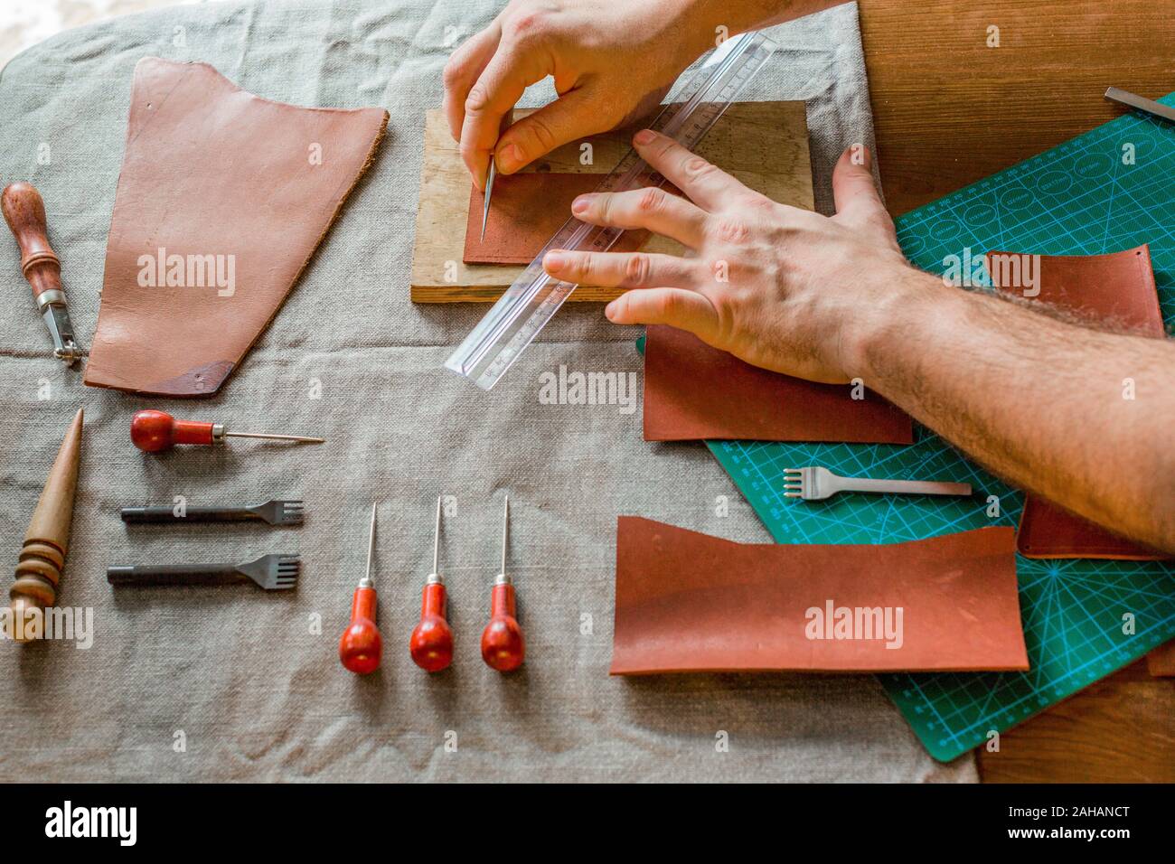 Il processo di lavorazione della borsa in pelle per denaro o messenger in pelle officina da maestro artigiano mani su lo sfondo della tabella. Tono colore immagine Foto Stock