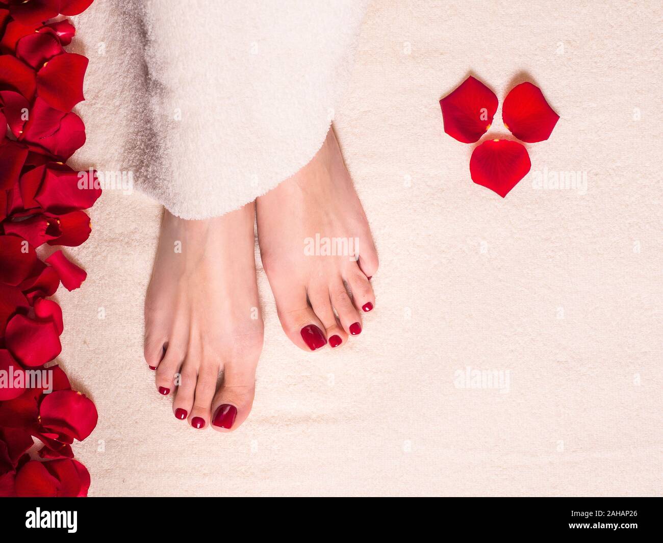 Bellissima femmina piedi per asciugamani in spugna con petali di rosa. Il vaso e tubo di cura della pelle crema. Spa e per la cura della pelle del concetto. Foto Stock