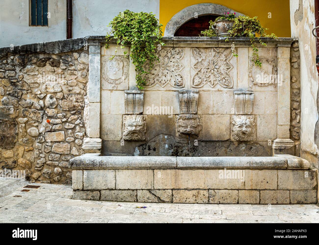 Fontana medievale con tre maschere e decorazioni scolpite, Sulmona Foto Stock