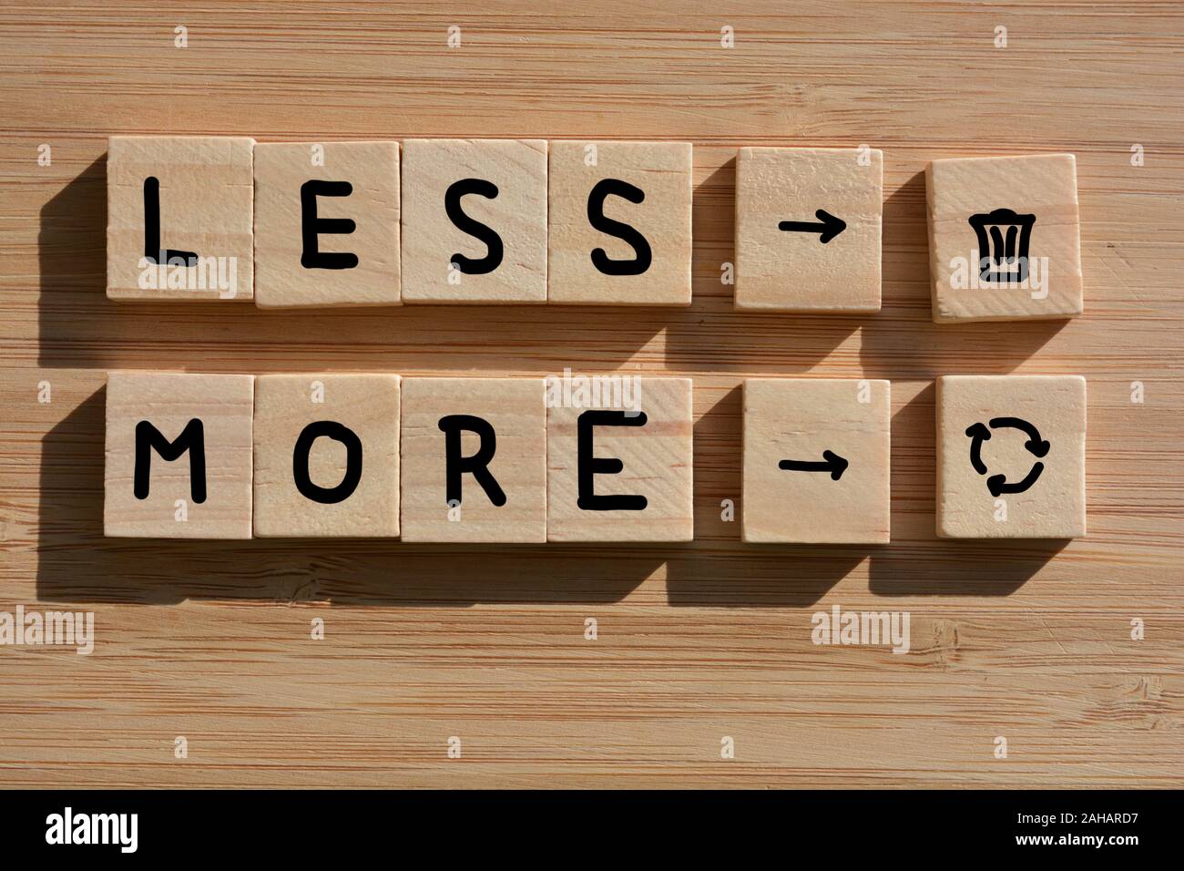Meno rifiuti più riciclo, in parole e simboli in 3d alfabeto di legno su blocchi di legno di bambù sfondo Foto Stock