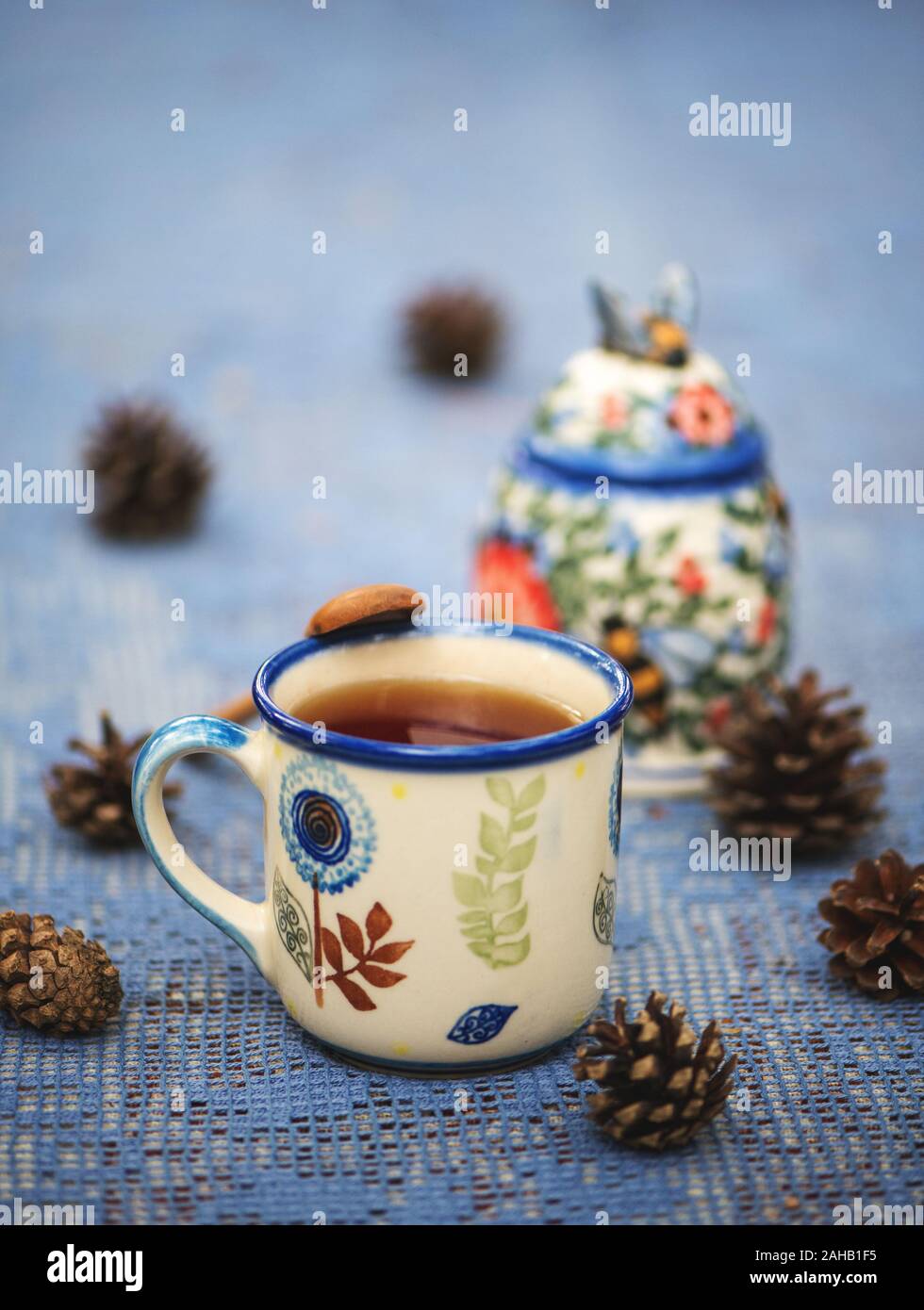 Freschi Tè alle erbe con miele in una tazza di ceramica su un blu tovaglia di pizzo outdoor Foto Stock