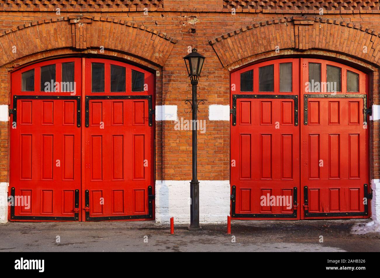 Un frammento di un vecchio edificio in mattoni rossi con due luminose Red Gate e un lampione. Sfondo vintage. Un contesto unico per la scelta di due opzioni Foto Stock