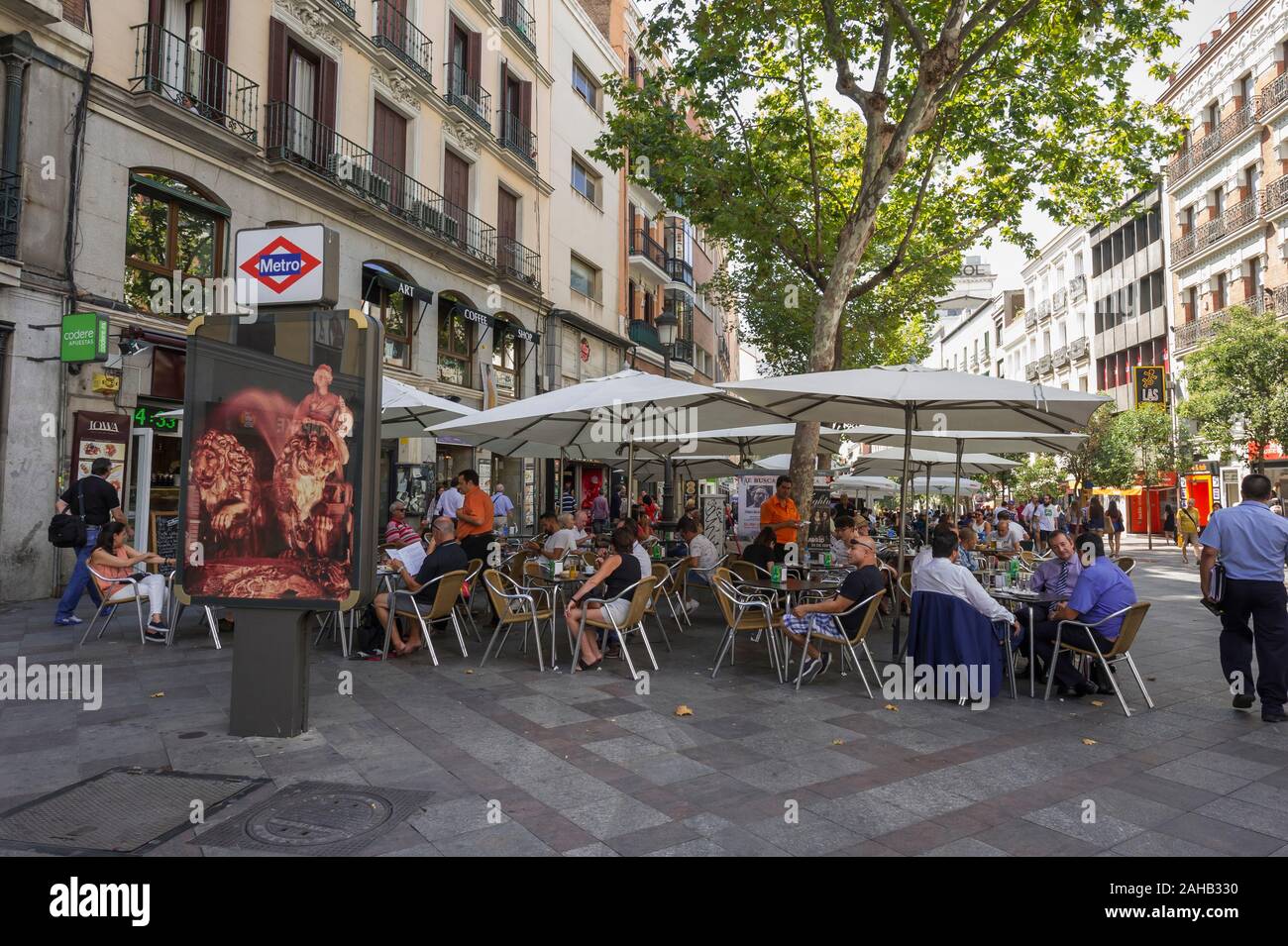 La gente seduta sotto grandi ombrelloni in un cafe' sul marciapiede di Madrid in Spagna Foto Stock