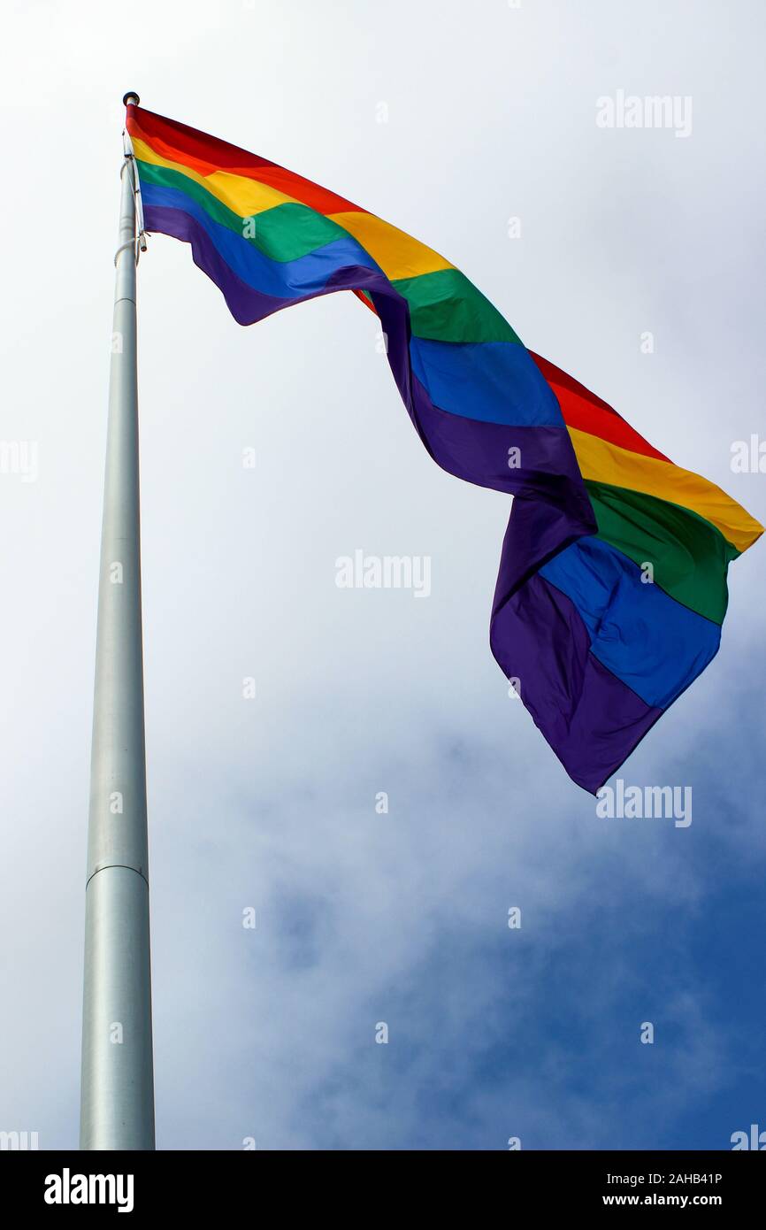 Basso angolo vista della bandiera arcobaleno sul pennone contro la metà cielo nuvoloso nel quartiere Castro di San Francisco, Stati Uniti d'America Foto Stock