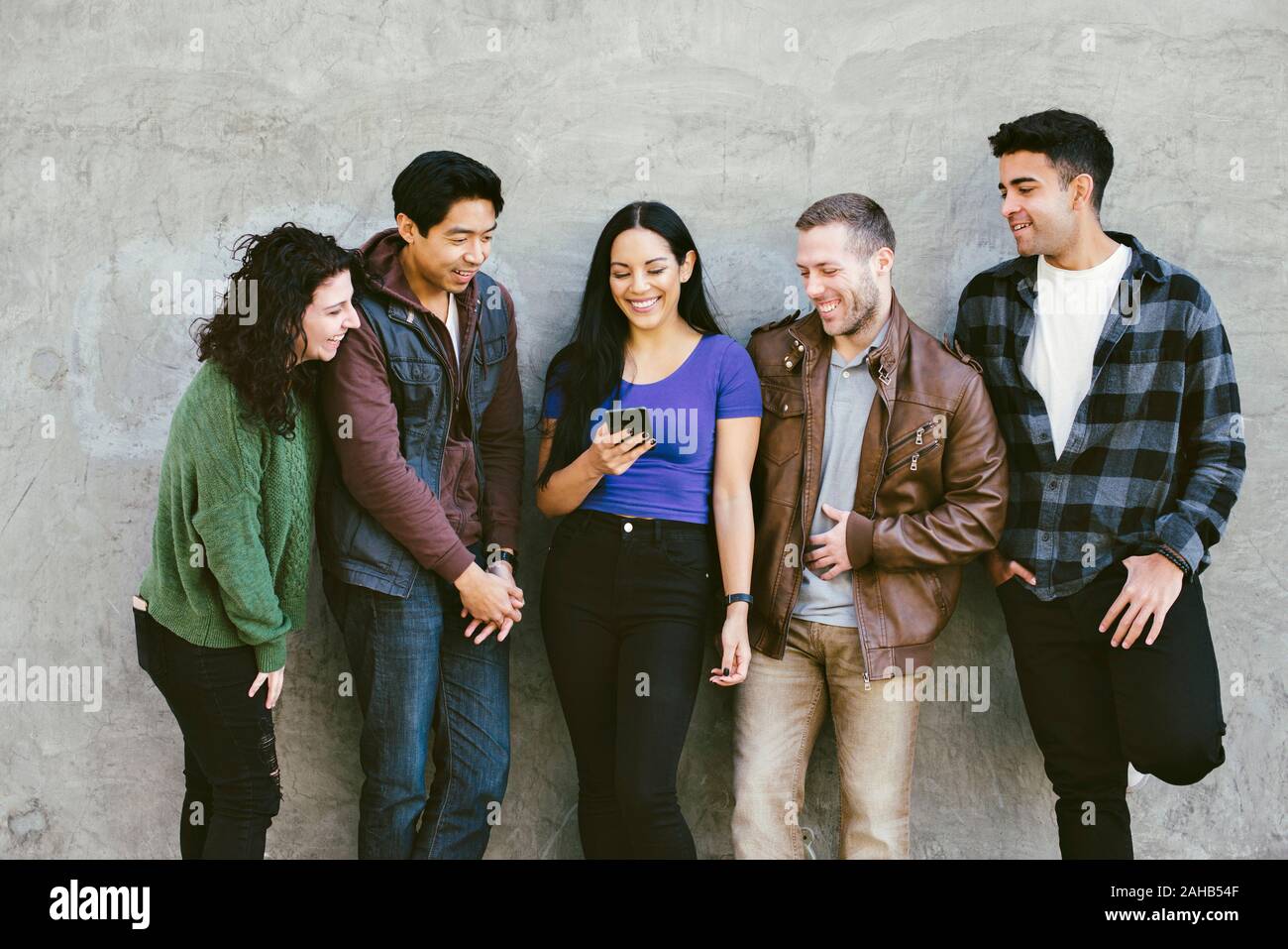 Cinque amici a ridere e divertirsi mentre si sta guardando un telefono cellulare durante la guida diurna - Concetto di felicità e insieme Foto Stock