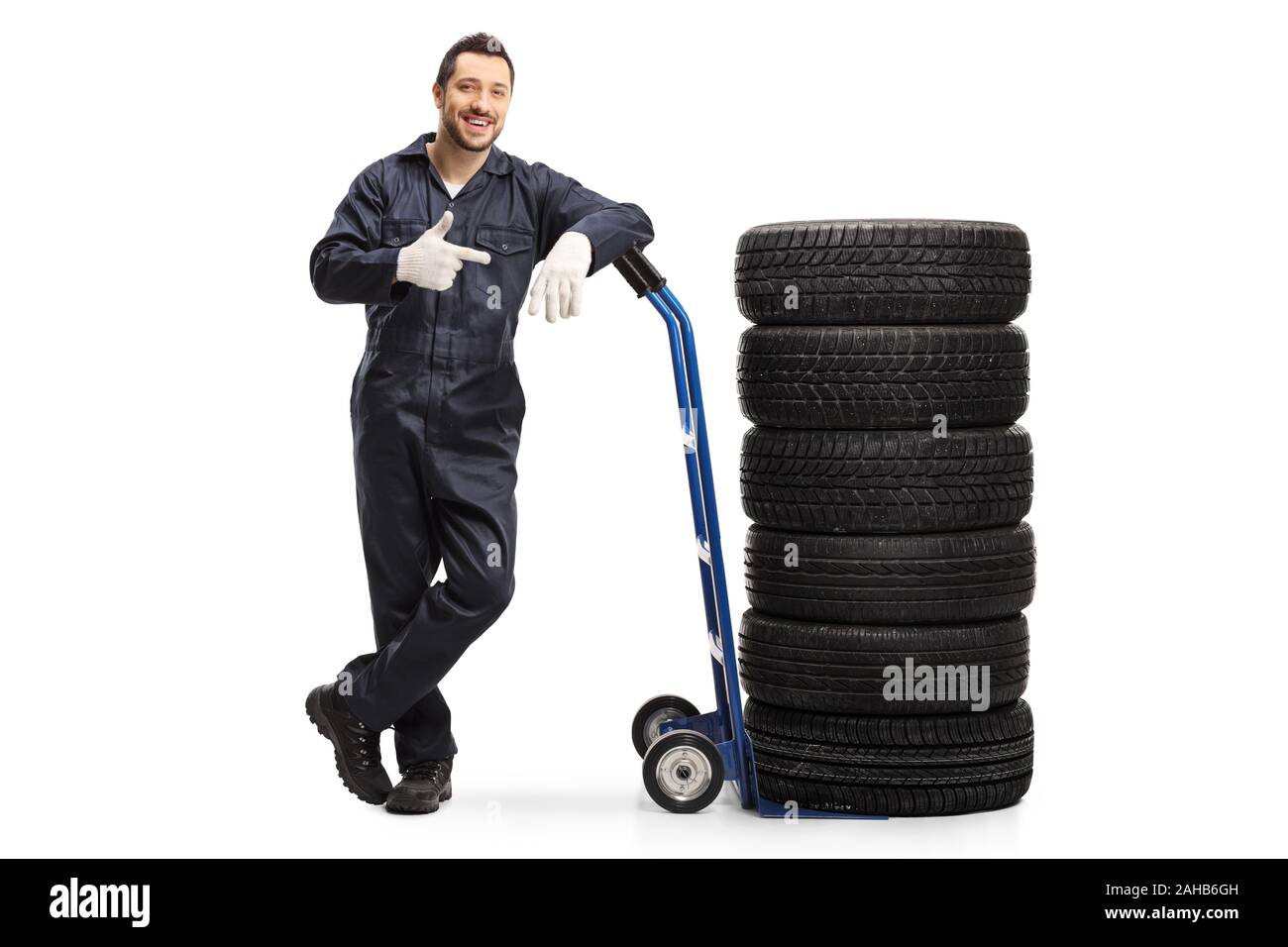 A piena lunghezza Ritratto di un meccanico di automobili in un uniforme in piedi con pneumatici di un carrello di isolati su sfondo bianco Foto Stock