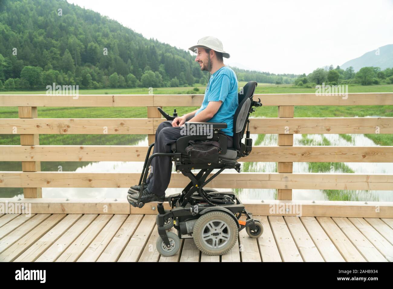 Disabilitato giovane in sedia elettrica su un lungomare godendo della sua libertà e della sua osservazione della natura Foto Stock