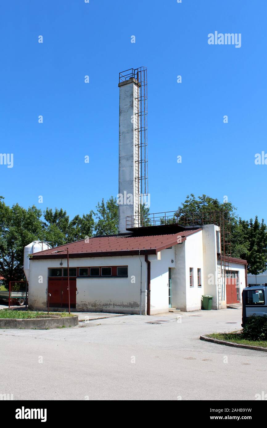 Piccolo edificio industriale di fronte alta e stretta rettangolo bianco camino in calcestruzzo con scale di metallo fissata con tondi di acciaio tunnel di sicurezza Foto Stock