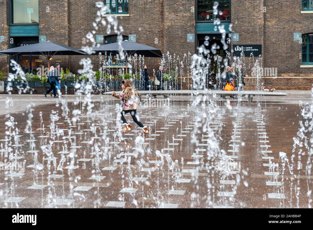 Ragazza giovane corre attraverso una fontana di acqua a Londra, Regno Unito. Foto Stock
