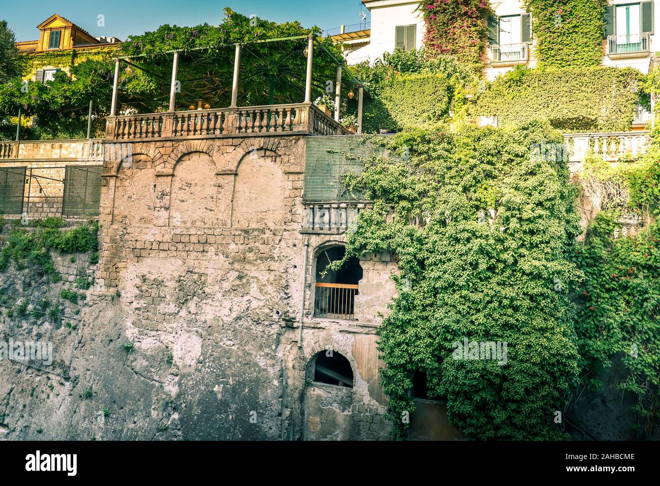 Vista rurale del muro di pietra coperto di piante verdi in via di Sorrento, Italia. Foto Stock