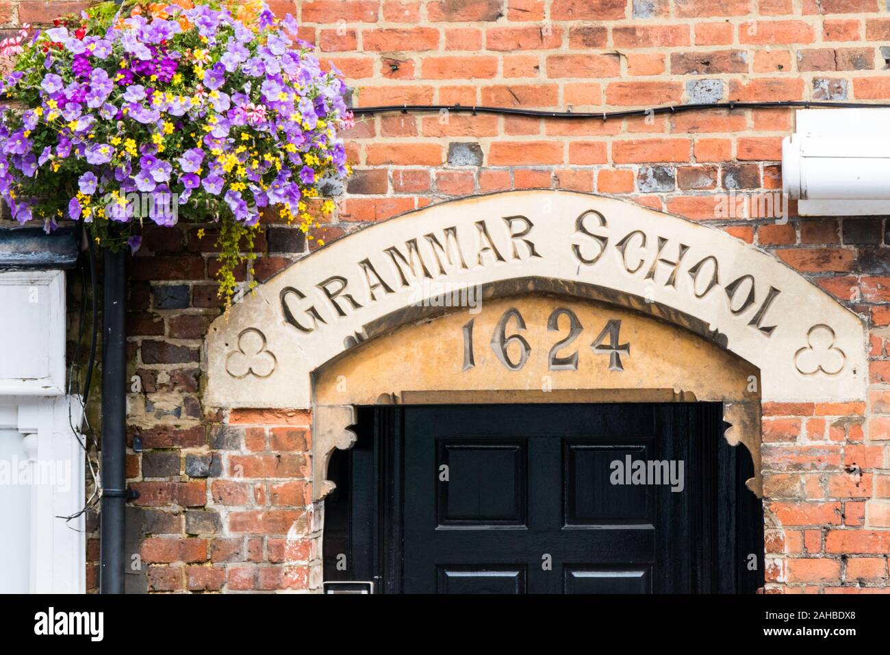 Architrave sopra l'ingresso alla vecchia scuola di grammatica datata 1624 e appeso cestello. Foto Stock