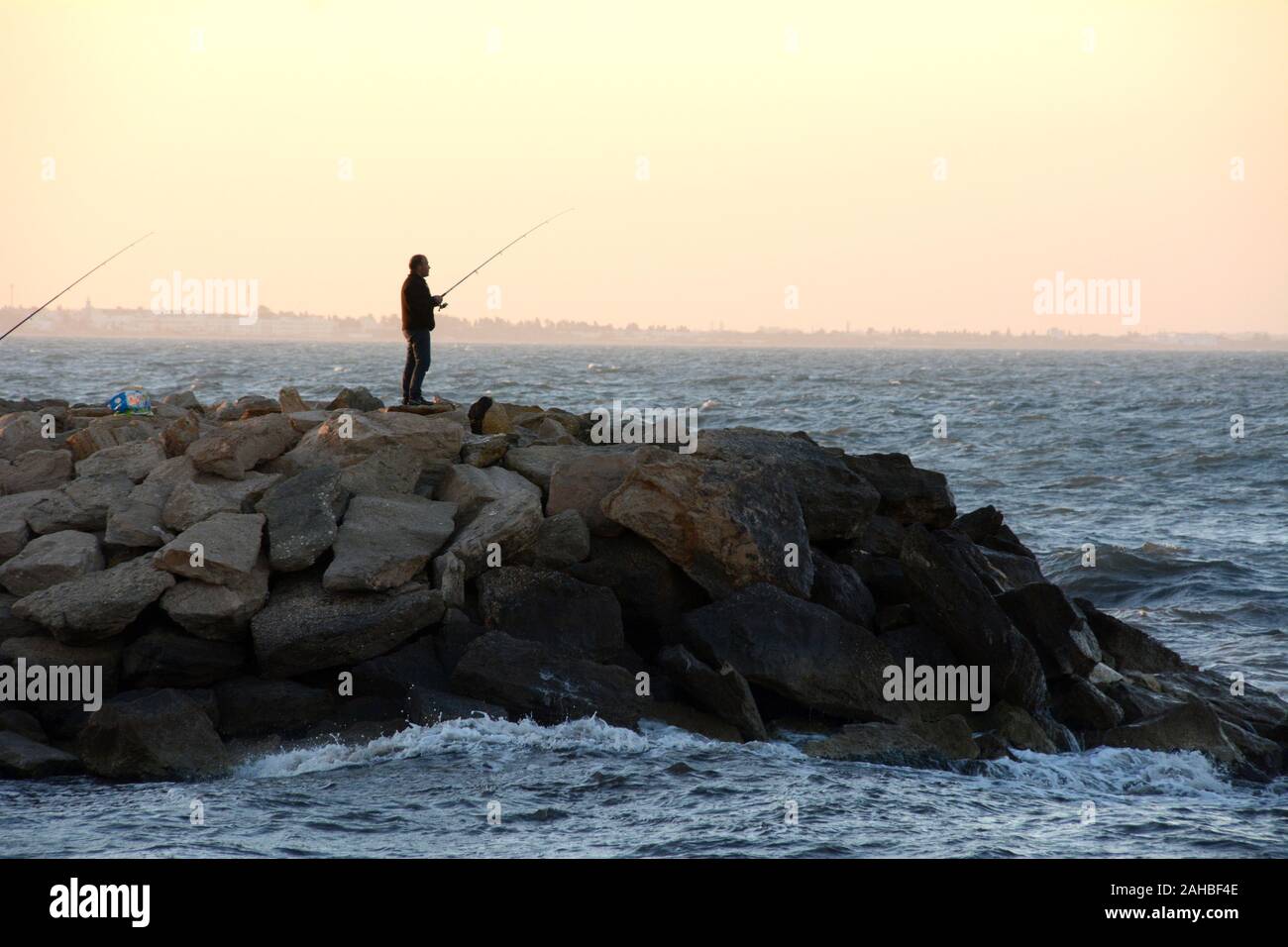 Un uomo tunisino la pesca al tramonto a bordo della vecchia città di Mahdia sulla costa mediterranea della Tunisia. Foto Stock
