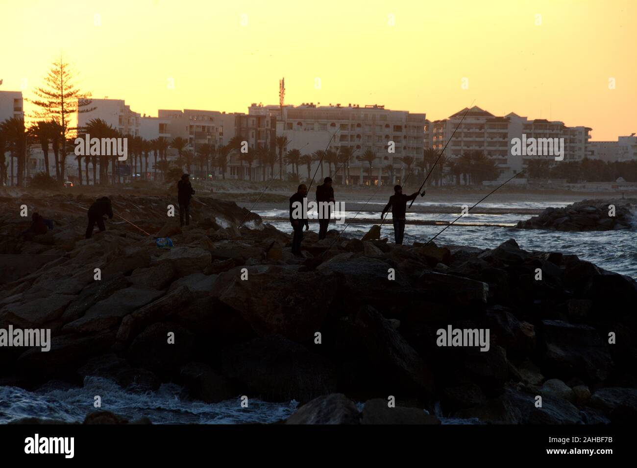 Un gruppo di uomini tunisini la pesca al tramonto nella città di Mahdia sulla costa mediterranea della Tunisia. Foto Stock