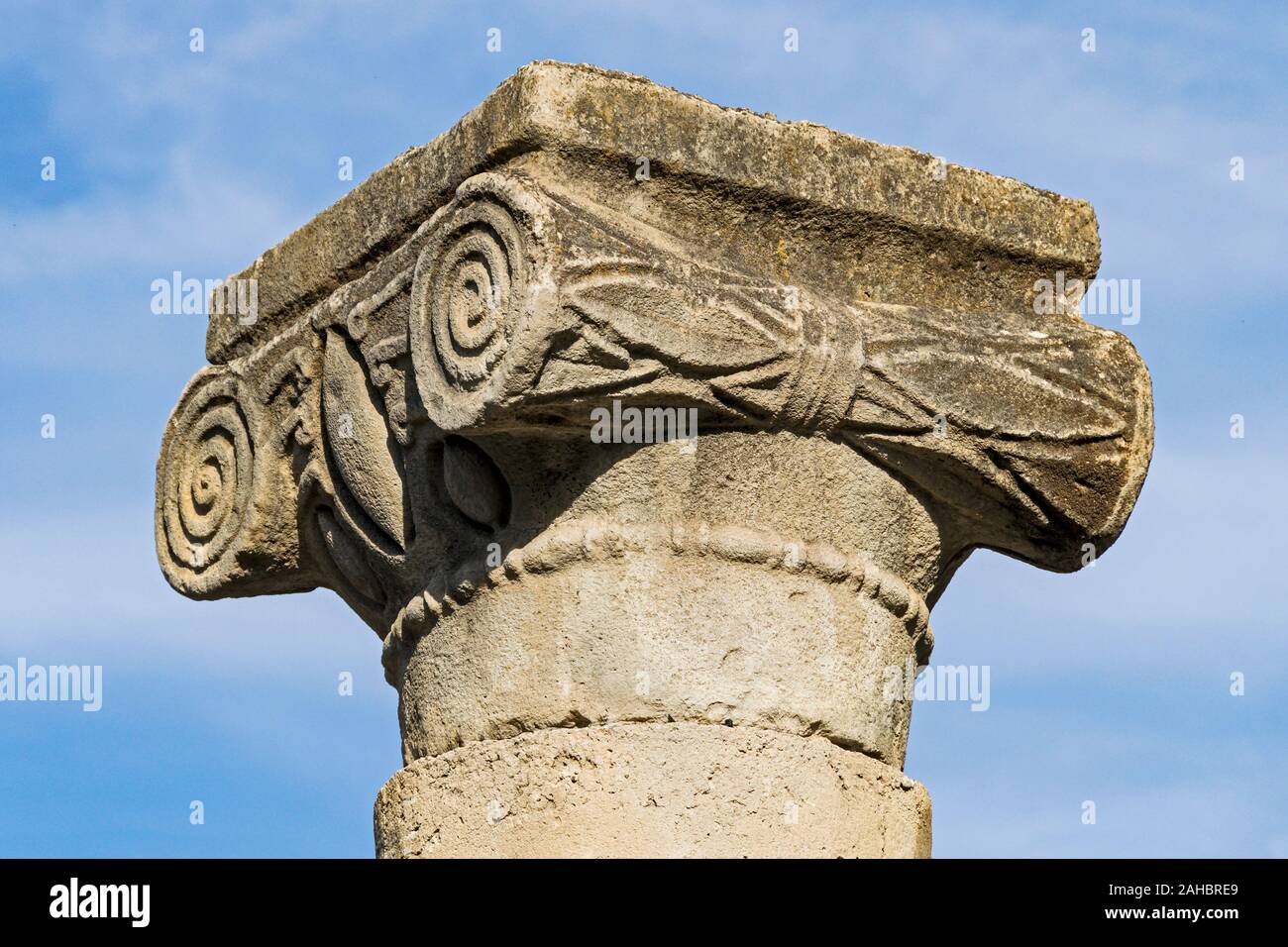 Primo piano di un classico greco capitale ionica al Talmud ser sito archeologico di Katzrin in Israele contro un poco nuvoloso cielo blu Foto Stock
