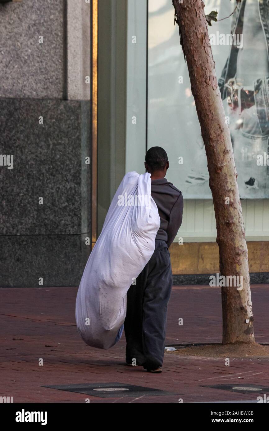 Assunta la persona senza dimora su Market Street con i suoi averi in un sacco bianco in San Francisco, Stati Uniti d'America Foto Stock