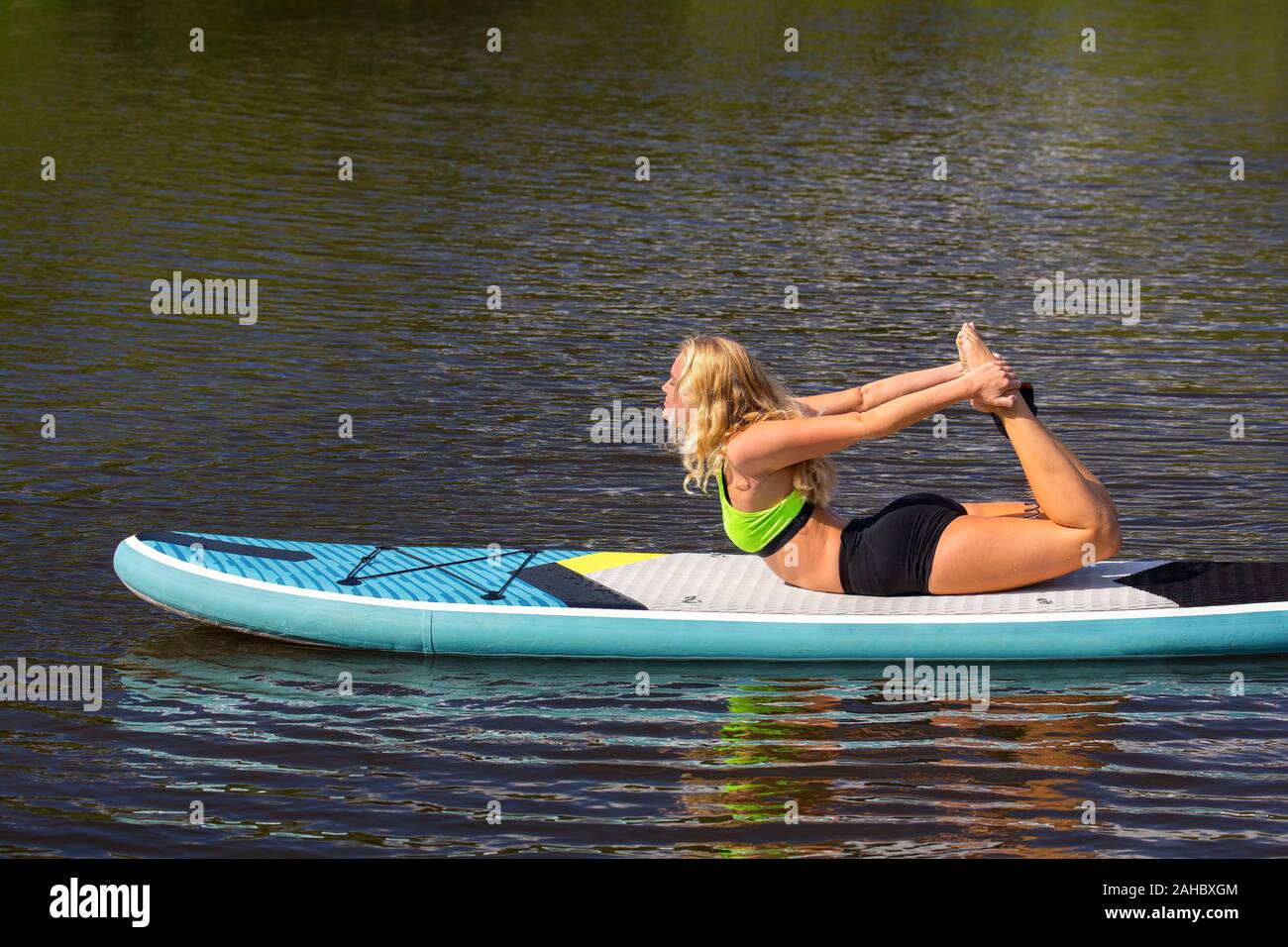 Bionda donna caucasica la pratica dello yoga postura sul SUP nel fiume Foto Stock