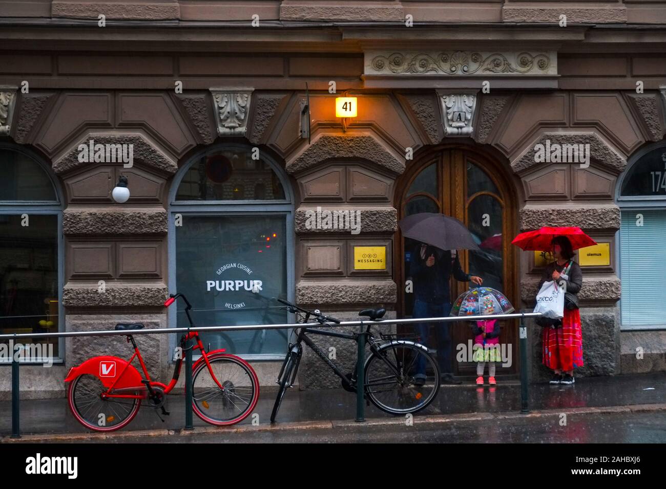 Tre persone con ombrelloni in un temporale, Helsinki, Finlandia Foto Stock