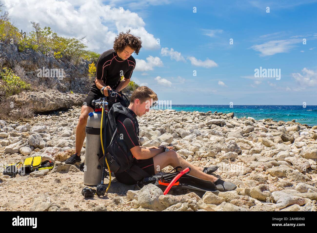Due giovani tuffatori caucasica sulla spiaggia la preparazione per le immersioni dell'isola Bonaire Foto Stock