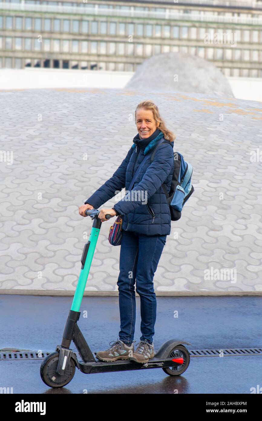 Donna alla guida di scooter elettrico sulla strada in Finlandia Foto Stock