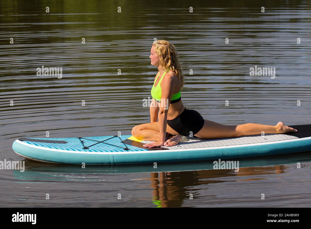 Giovane donna europea di yoga postura swan sulla paletta bordo in acqua Foto Stock