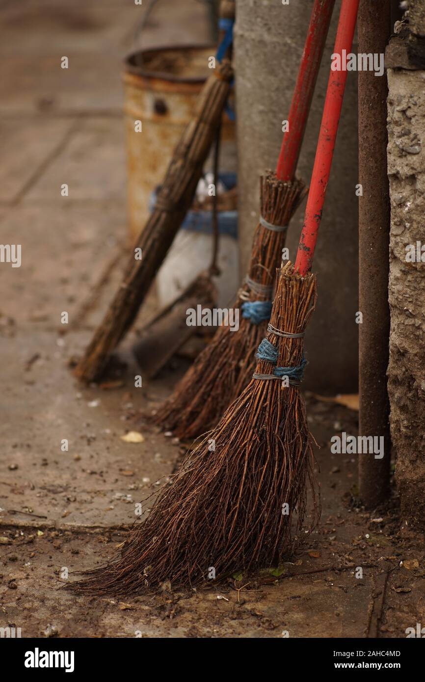Set di vecchia maglia di vimini scope in un umido cortile rurale. Foto Stock