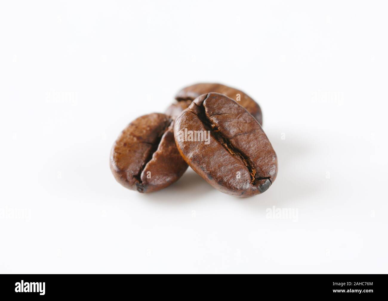Tre chicchi di caffè tostati su sfondo bianco Foto Stock