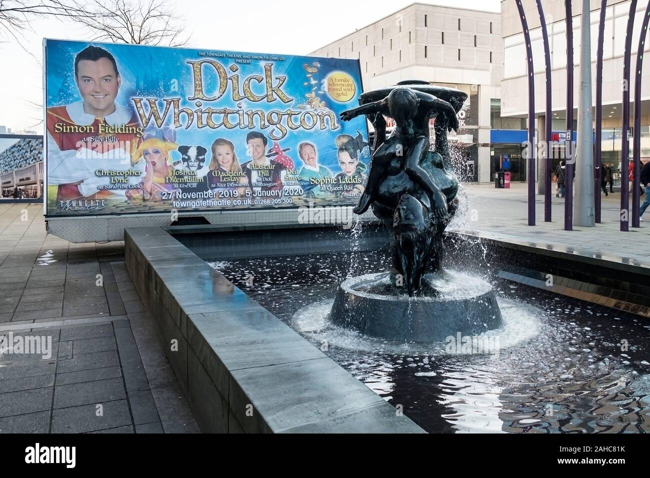 Un grande cartellone pubblicitario per la pantomima di Natale presso il Teatro Towngate posizionato accanto al famoso la madre e il Bambino scultura fontana in Foto Stock