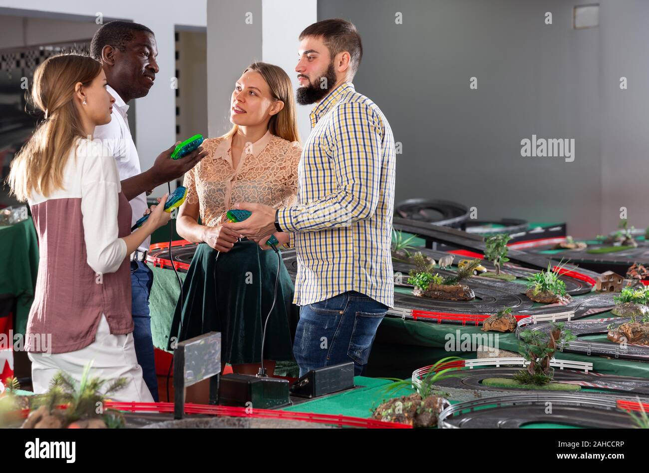 Gli amici di discutere i risultati dei giochi su toy slot racing car via Foto Stock