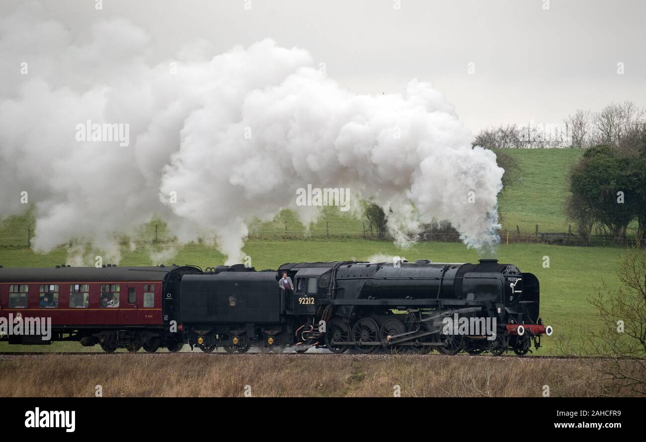 Locomotiva a vapore 92212, Ferrovie britanniche standard di classe 9F, rende il modo lungo la metà Hants railway, noto anche come la linea di crescione, tra Ropley e Medstead in Hampshire. Foto Stock