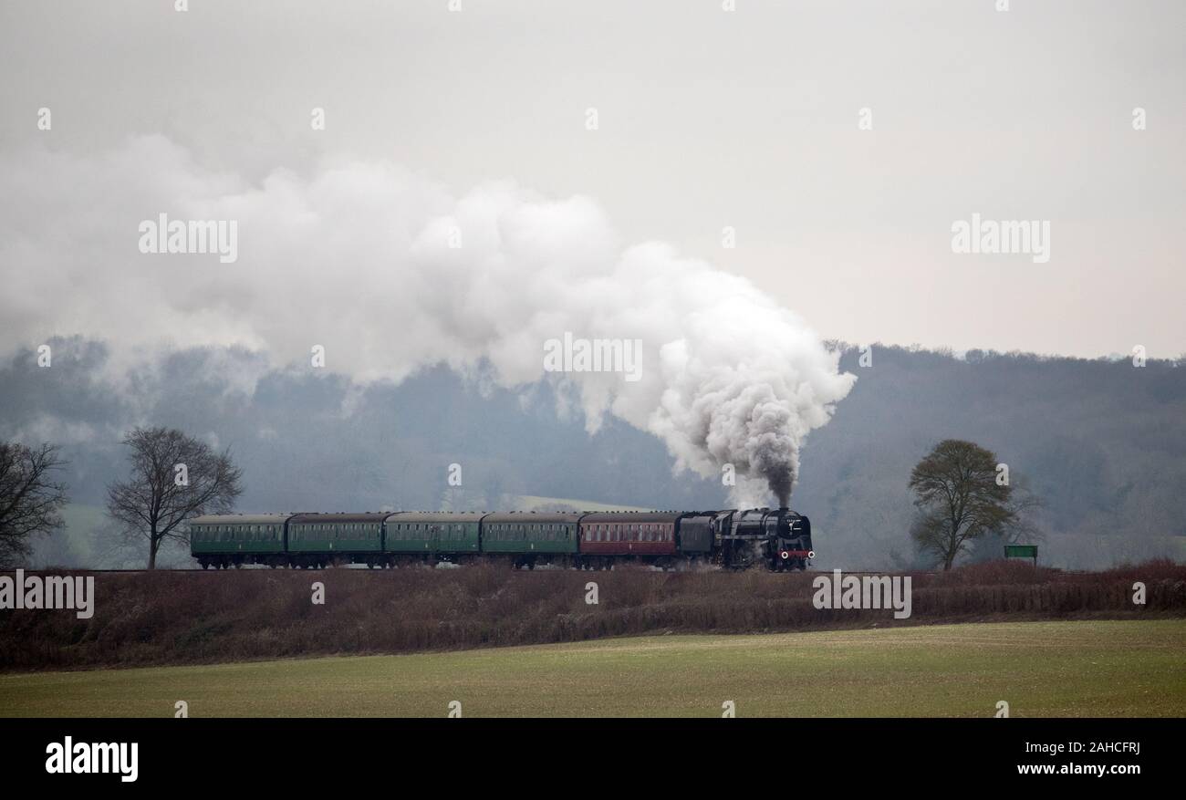 Locomotiva a vapore 92212, Ferrovie britanniche standard di classe 9F, rende il modo lungo la metà Hants railway, noto anche come la linea di crescione, tra Ropley e Medstead in Hampshire. Foto Stock