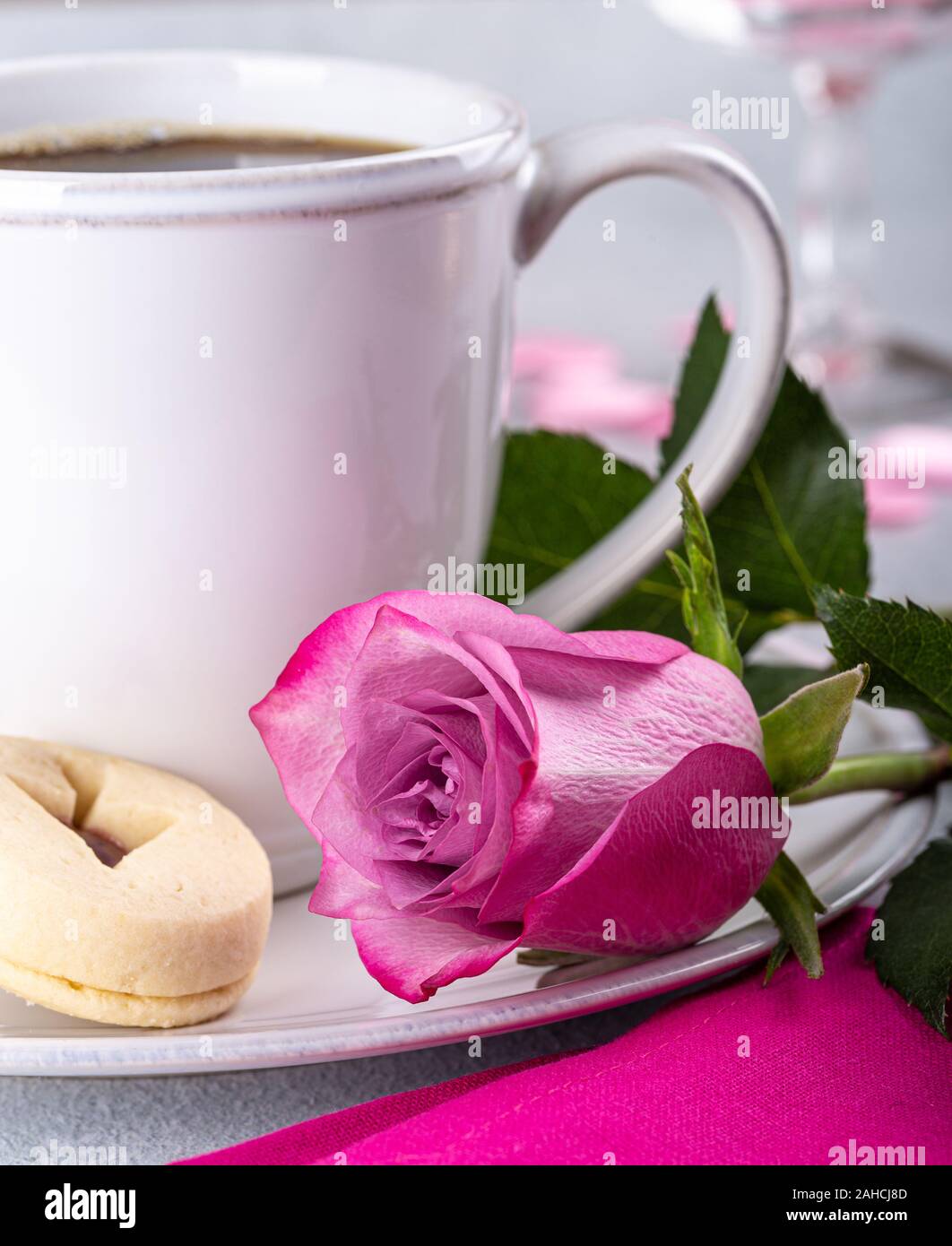 Primo piano di una rosa rosa per il giorno di San Valentino e una tazza di caffè su una piastra Foto Stock