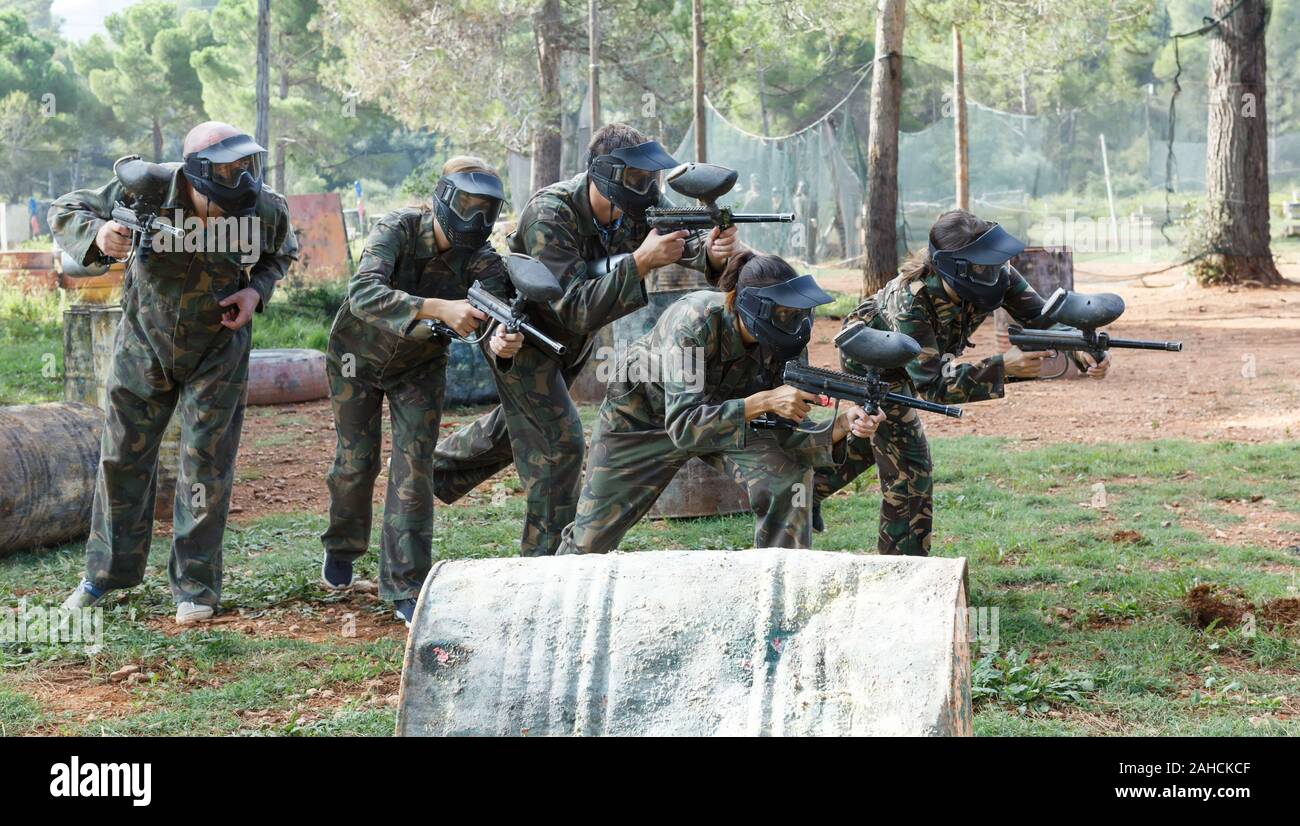 Dynamic paintball battaglia all'esterno. Un gruppo di persone in piena attrezzatura paintball attaccando squadra opposta Foto Stock