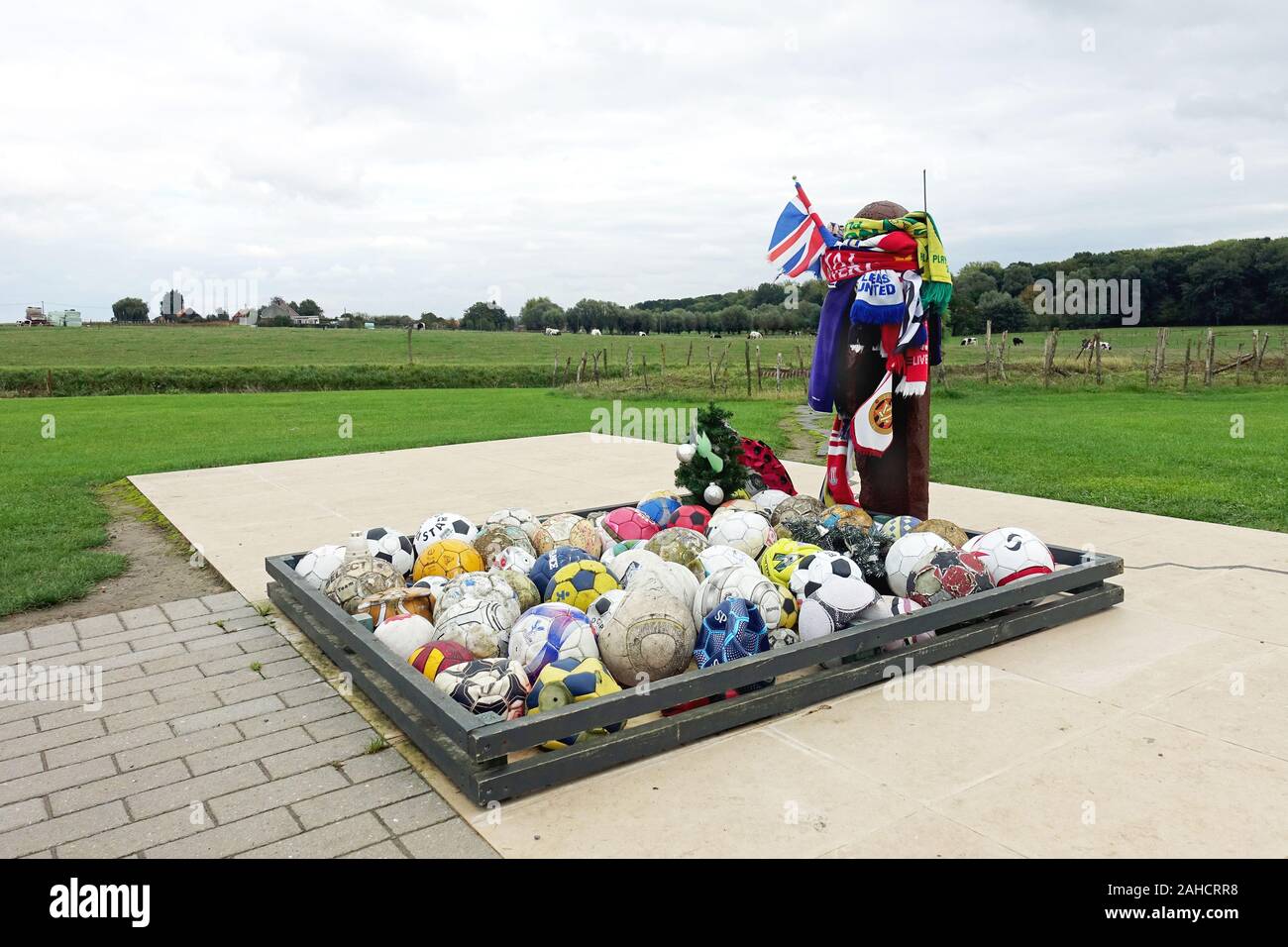 Le persone lasciano palloni e cimeli del club presso il memoriale di UEFA al 1914 NATALE TREGUA e partite di calcio tra inglesi e soldati tedeschi Foto Stock