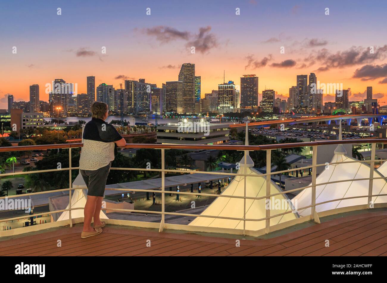 La donna che si affaccia sulla skyline di Miami dopo il tramonto da una nave da crociera della ringhiera Foto Stock